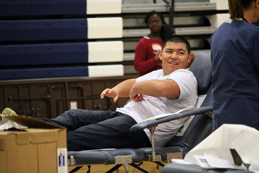 Laughing wiht another student to his left, junior Isaiah Florez waits for a nurse to walk over to him on Friday's Blood Drive.